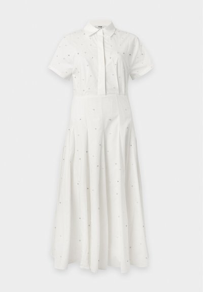 Robe blanche à manches courtes avec col, boutonnée sur le devant et petites ornements argentés dispersés, avec une taille cintrée et une jupe évasée.