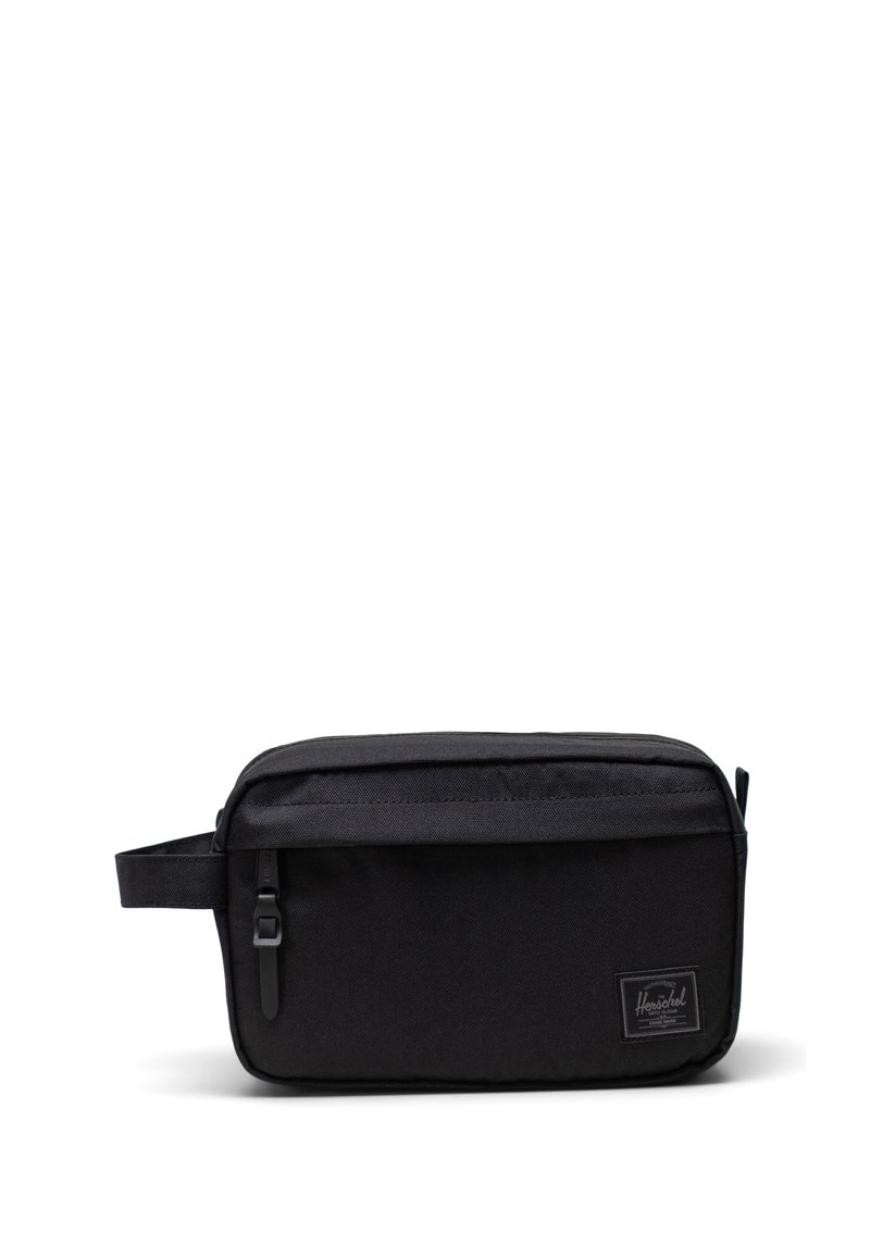 Neceser negro hecho de tela duradera. Forma rectangular con un cierre superior, asa lateral y un discreto parche con el logotipo en la parte frontal.