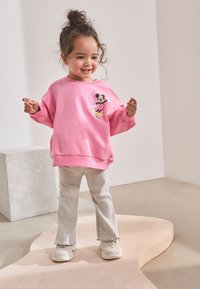 Roosa dressipluus, millel on Mickey Mouse'i graafika, kombineeritud helehallide lõdvalt lõigatud pükstega, millel on narmendavad äärised, ja valgete tossudega. Sile, mugav tekstuur.