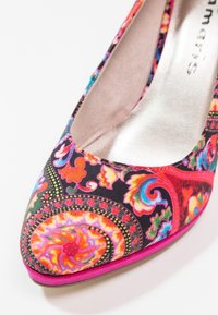 Chaussure à bout pointu avec des motifs floraux et cachemire multicolores vibrants, comprenant des détails roses, orange, bleus et verts sur un fond noir.