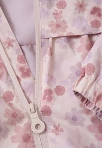 Jachetă roz cu model floral, realizată dintr-un material ușor, cu închidere prin fermoar și manșete cu elastice, decorate cu diverse flori rosii și mov.
