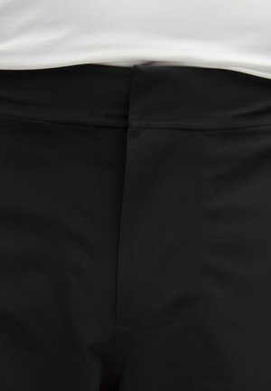 Zwarte stof, gladde textuur, op maat gemaakt ontwerp met een verborgen rits en een nette tailleband. Geleverd zonder zichtbare zakken of versieringen.