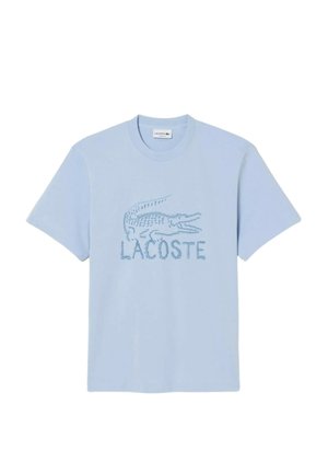 Camiseta de manga corta azul claro con logo de cocodrilo bordado y texto "LACOSTE" centrados en el pecho.