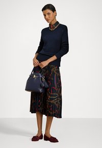 Pulover tricotat bleumarin, fustă plisată cu model de lanț auriu și roșu, geantă bleumarin cu ciucure și pantofi plata burgundii.