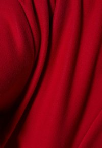 Tela roja con una textura suave, apariencia lisa y pliegues caídos, que exhibe una rica saturación de color y una sutil profundidad en la superficie.