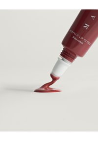 Czerwony błyszczyk w tubce z ostrym aplikatorem, wylewający gładki, błyszczący burgundowy produkt na białą powierzchnię.