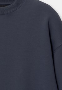 Felpa blu scuro realizzata in tessuto testurizzato, con collo a girocollo a costine e vestibilità leggermente loose. Colore uniforme e liscio, senza motivi visibili.
