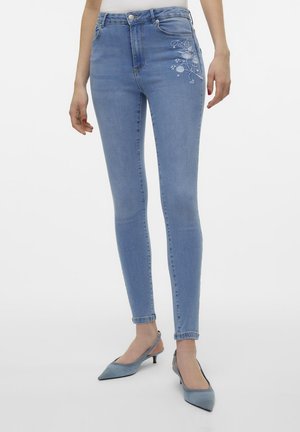 Lyseblå høytlivde skinny jeans med blomsterbroderi på venstre lår. Laget av denim, med en tettsittende design og frontlommer.