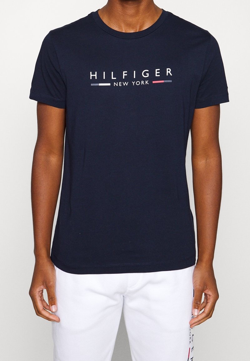 Námořnická modrá bavlněná tričko s kulatým výstřihem a krátkými rukávy, s bílým, červeným a modrým textem "HILFIGER NEW YORK".