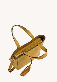 Sac en cuir jaune moutarde avec doubles poignées, fermeture éclair et un pompon décoratif sur fond blanc uni.