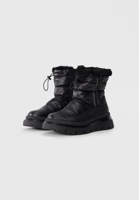 Zwarte geïsoleerde enkelboots met nepbontafwerking, een luchtige textuur, een dikke rubberen zool en een trekkoordsluiting voor een veilige fit.