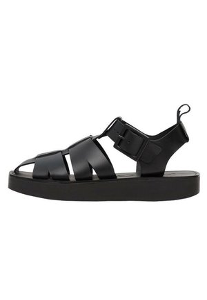 Sandale en cuir noir avec semelle épaisse, plusieurs brides sur les orteils et le pied, grande boucle sur le côté et languette au talon.