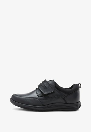 Chaussure en cuir noir avec une finition lisse, dotée de deux bandes Velcro et d'un capuchon de pied texturé. La semelle est robuste et présente une légère courbure.