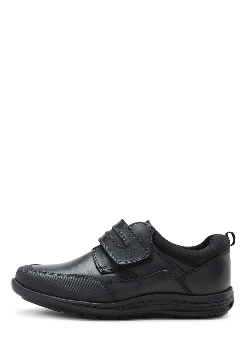 Chaussure en cuir noir avec une finition lisse, dotée de deux bandes Velcro et d'un capuchon de pied texturé. La semelle est robuste et présente une légère courbure.