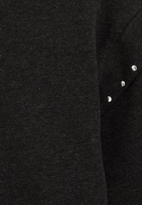 Tessuto di maglia nero con una texture liscia, impreziosito da cinque borchie metalliche lungo la spalla per un tocco di stile.