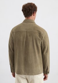 Olivgrüne Wildlederjacke mit taillierter Form, Hemdkragen und knopfbaren Manschetten; zeichnet sich durch eine glatte Textur und minimale Nähdetails aus.