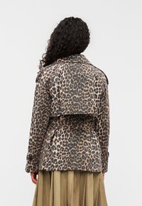 Καμπαρντίνα με λεοπαρντ σχέδιο από υφασμάτινη ύφανση, με ζώνη στη μέση, μεγάλο γιακά και λεπτομέρειες στους μανσέτες, εμφανιζόμενη από πίσω.