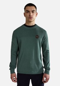 Groen gebreid sweatshirt met een gevarieerd patroon op het bovenpaneel, geribbelde ronde hals en manchetten, met een cirkelvormige logopatch op de borst.
