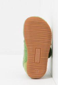 Zielone filcowe kapcie z gumową podeszwą, wyposażone w teksturowane wzory bieżnika oraz z logo producenta. Metki wskazują rozmiar 19.