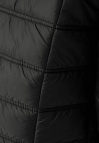 Černá péřová bunda s horizontálním prošíváním. Hladká, lehká tkanina s matným povrchem a jemným leskem. Žádné viditelné loga ani vzory.