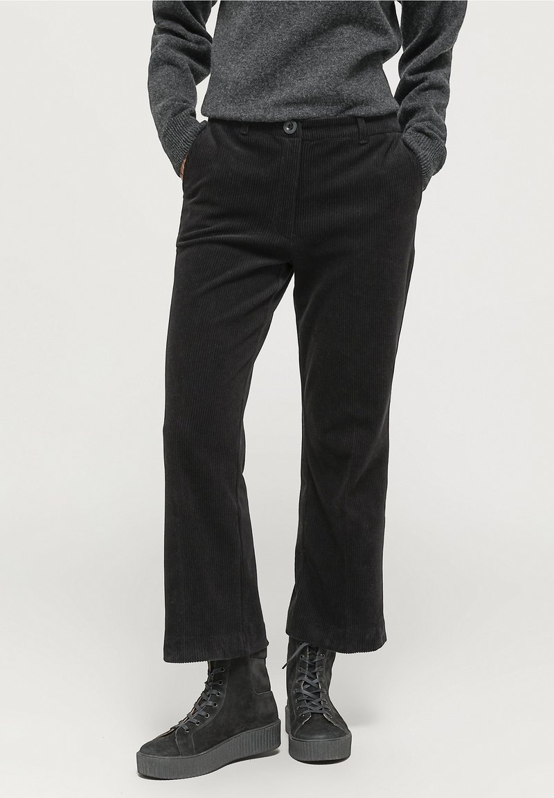 Svarta manchesterbyxor med platt front, raka ben, två sidofickor och knappstängning. Kombineras med svarta snörda plattformskängor.