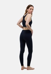 Ensemble d'entraînement bleu marine comprenant un débardeur court avec une bande métallique et un legging taille haute. Tissu lisse et extensible avec un design ajusté.