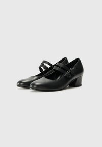 Black leather Mary Jane shoes featuring a rounded toe, two wide straps with buckles, and a low block heel. Smooth texture and sleek design.