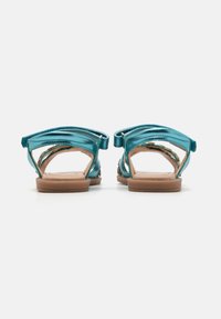 Blå metalliske sandaler med åpen bakdesign, justerbar stropp og polstret såle. Har en jevn tekstur og minimalistisk stil.