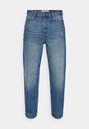 Jean en denim bleu clair avec une coupe décontractée. Présente un délavage subtil, des marques d'usure sur le devant et un léger effet usé sur le bas de la jambe.