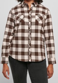 Camicia a quadri marrone e crema con colletto, due tasche sul petto e maniche lunghe con polsini a bottone. Tessuto in cotone.