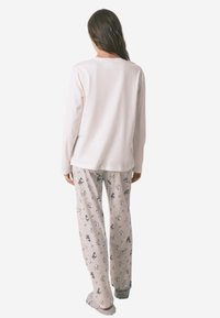 Wit, langmouwtop gecombineerd met lichtgrijze, gestreepte pyjamabroek met cartoonachtige ontwerpen en een ontspannen pasvorm. Zachte, gezellige texturen.