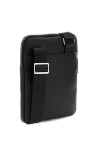 Sac en messager synthétique noir avec une finition texturée, fermeture zippée, sangle réglable et une poche frontale fonctionnelle.