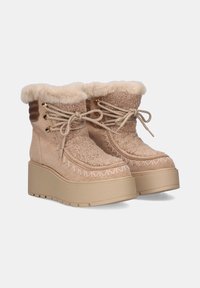 Botas de plataforma beige con ribete de piel sintética, parte superior de tela texturizada, costuras decorativas y diseño con cordones. Suela gruesa sólida para mayor soporte.