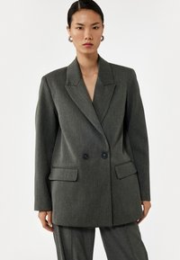 Grå, overdimensioneret blazer med slidsekrave, dobbeltknaplukning, to forlommer og glat stoffets struktur.