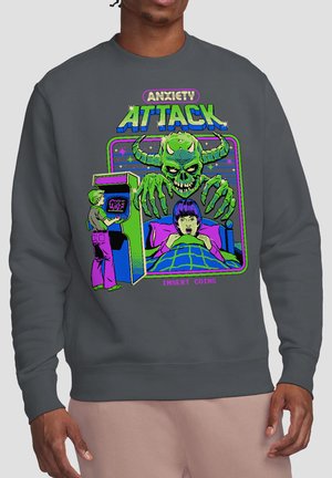 Graphic on dark gray sweatshirt shows a green horned skull monster looming over a scared person in bed, with a person playing an arcade game nearby.