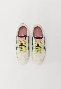 Baskets avec une tige en cuir crème, des accents verts et une languette rose. Elles présentent des lacets verts et une doublure intérieure bordeaux. Semelle en caoutchouc.