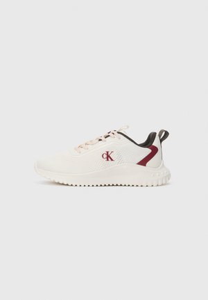 White athletic sneaker with pink laces, burgundy heel accents, and a red CK logo on the side, set against a plain background.