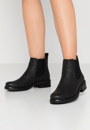 Bottines noires en cuir avec des panneaux latéraux élastiques, un bout arrondi et un petit talon carré. Texture lisse avec un design minimaliste.