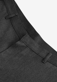 Tissu noir avec une texture lisse, comportant une taille élastique et des passants de ceinture. Le design est simple, moderne, avec une silhouette épurée.