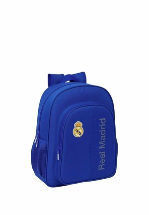 Niebieski plecak z logo i napisem Real Madryt, wyposażony w kilka zamykanych na zamek komór i siatkowe boczne kieszenie.