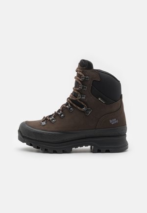 Bota de caminhada em couro castanho com um design de tornozelo alto, bico reforçado, atacadores em metal e sola de borracha texturizada para tração. Forro impermeável incluído.