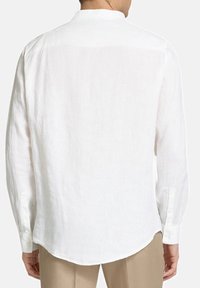 Camicia bianca a maniche lunghe in lino con colletto alla cinese, orlo arrotondato e polsini abbottonati, con una texture liscia e cuciture minime.