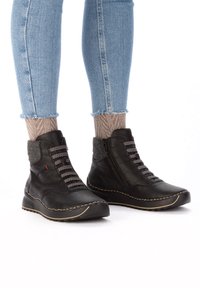 Bottines en cuir noir avec un accent en tissu texturé, dotées de lacets rayés, d'une fermeture éclair sur le côté et d'une semelle contrastée cousue.