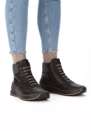 Bottines en cuir noir avec un accent en tissu texturé, dotées de lacets rayés, d'une fermeture éclair sur le côté et d'une semelle contrastée cousue.