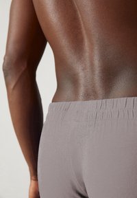 Grijze stretchstoffen shorts met een elastische tailleband, met een gladde textuur en een aansluitende snit die de contouren van het lichaam accentueert.