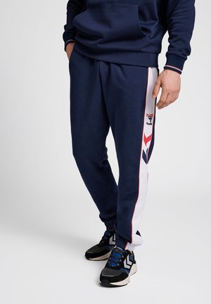 Navyblaue Jogginghosen mit weißen und roten Seitenteilen, elastischem Bund und gerippten Bündchen. Mit einem Logo am linken Oberschenkel und einer lässigen Passform.
