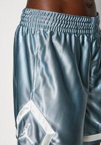 Lyseblå satengidrettsshorts med elastisk midje og en hvit brodert Jumpman-logo på en diamantlapp.