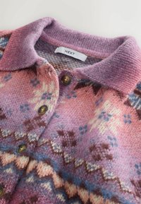 Neulekortti, jossa on vaaleanpunainen ja violetti väri, kuvioitu pinta, kauluskangas ja ruskeat napit. Brändilapussa lukee "NEXT."