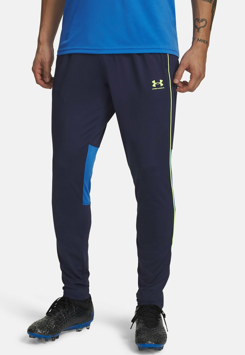 Marineblauwe sportbroek met blauwe accenten, voorzien van een getextureerd zijpaneel, een slanke pasvorm en contrasterende neon groene branding op het been.