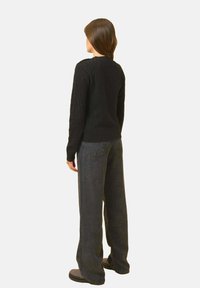 Czarny sweter w splot warkoczowy, okrągły dekolt, ściągacze na rękawach, zestawiony z ciemnymi, szerokimi dżinsami z wysokim stanem i płaskimi, teksturowanymi czarnymi butami.